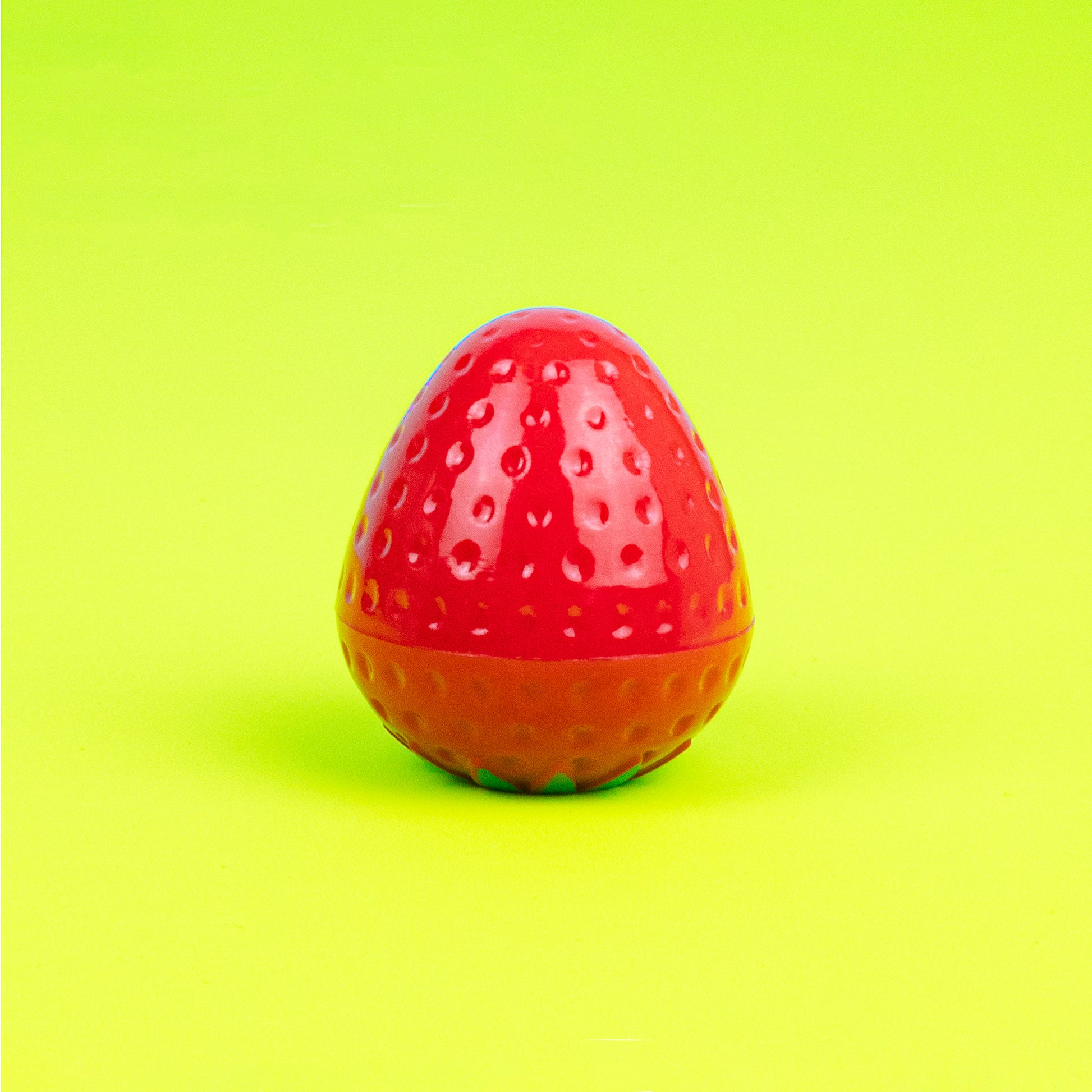 Strawberry lip balm in front of green background