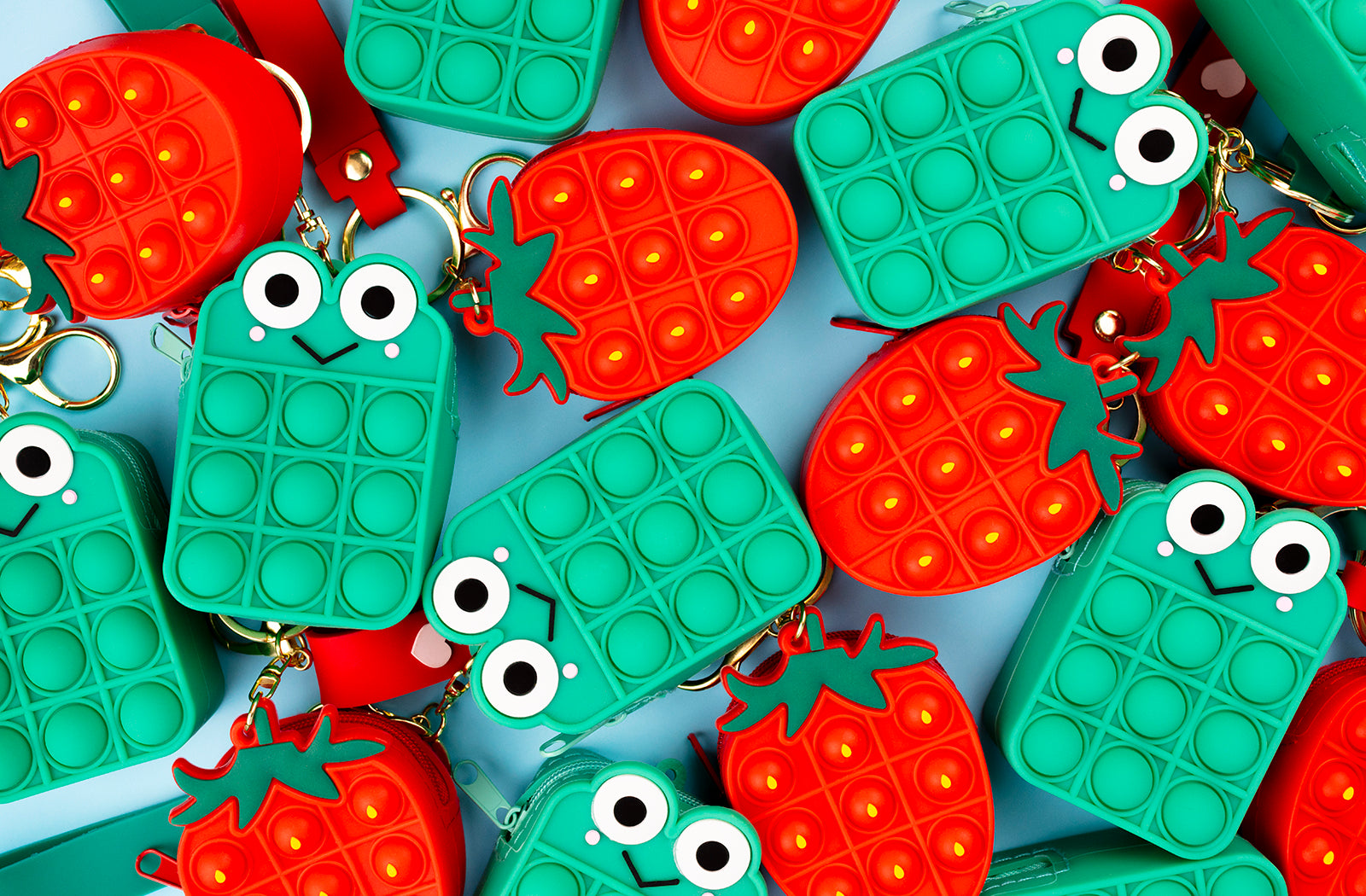 Frog pop it fidget toy and strawberry pop it bag arranged next to each other